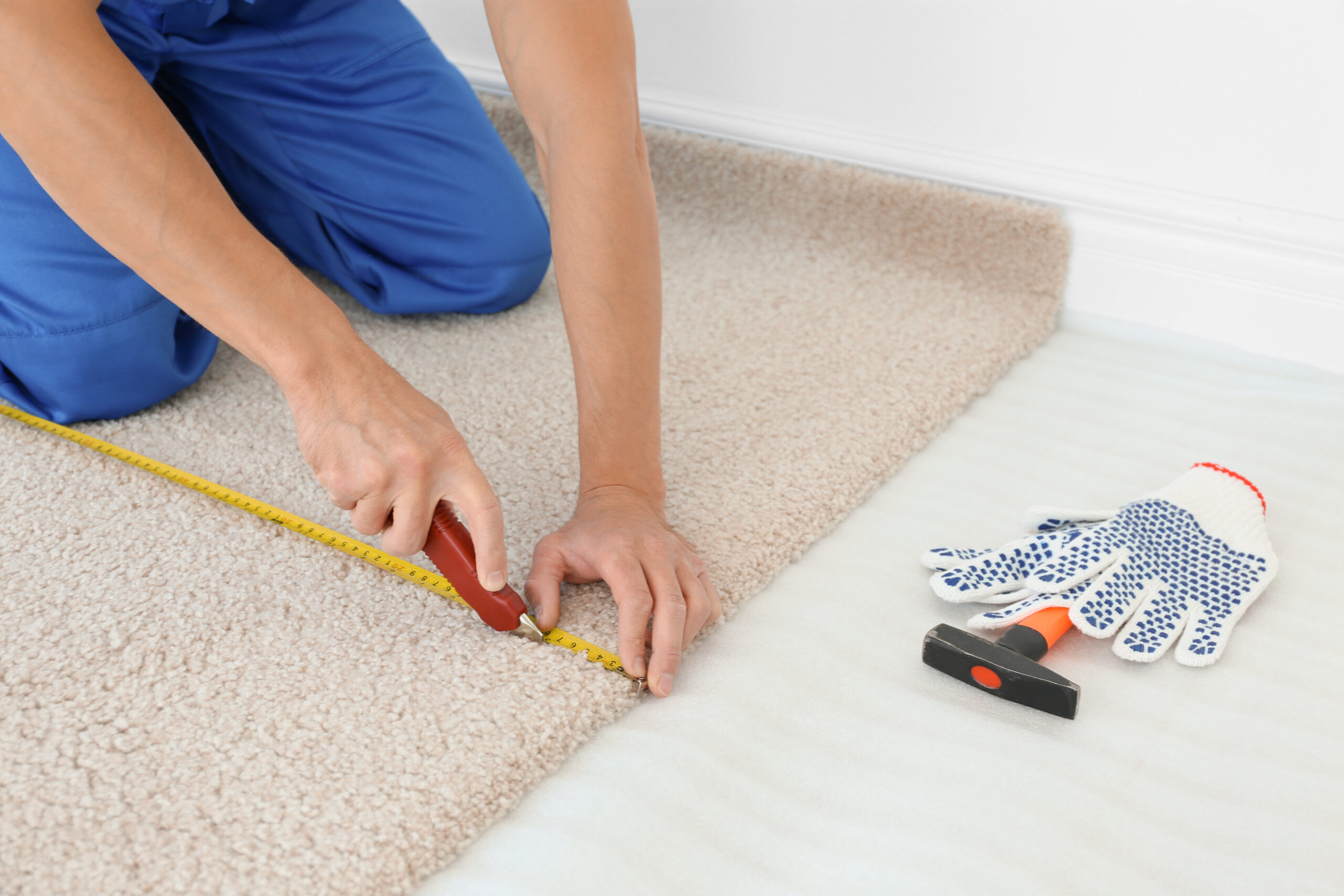 Worker using cutter while installing new carpet flooring in room